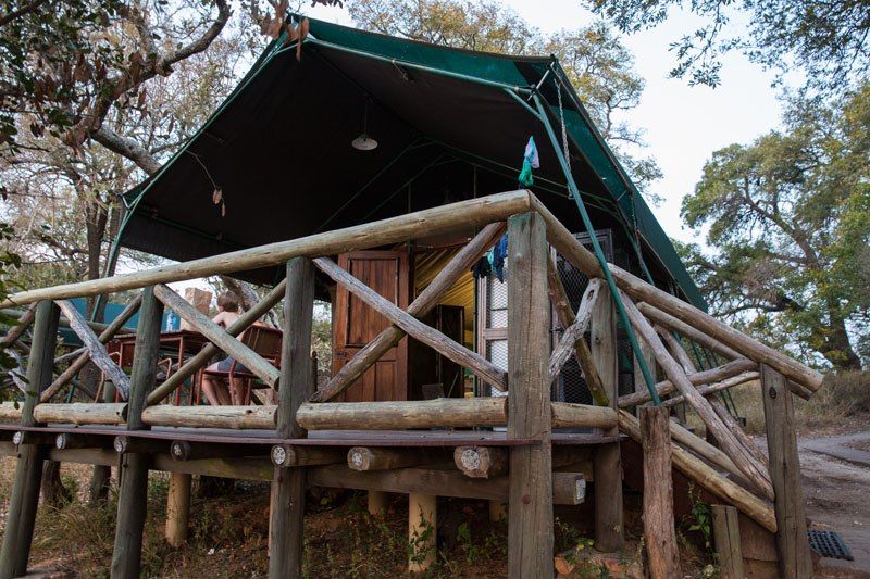 A permanent tent with wooden doors, and a green roof pitched on top of a raised wooden deck.