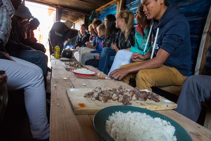 A tour group being served cow cheeks while visiting Soweto, South Africa.