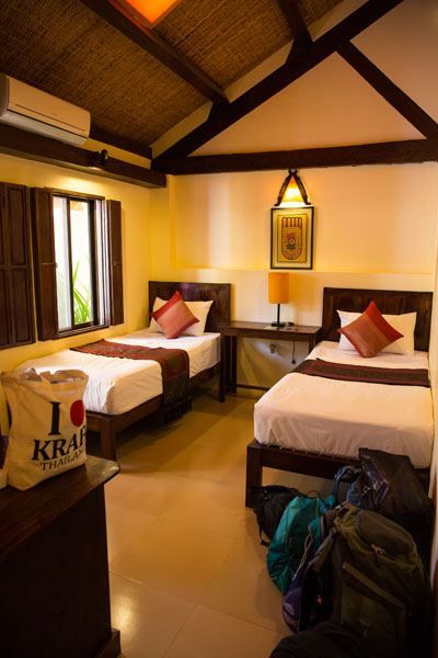 Two single beds in a kids' room with soft lighting and a wooden beamed ceiling at the Rikitikitavi Hotel, Kampot, Cambodia.