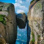 Kjeragbolten in Norway. Beneath the boulder, water and land is visible.