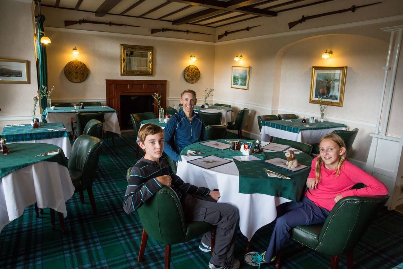Tim, Tyler and Kara sit in the dining room with a fireplace at the Glenmoriston Arms Hotel near Loch Ness in Scotland