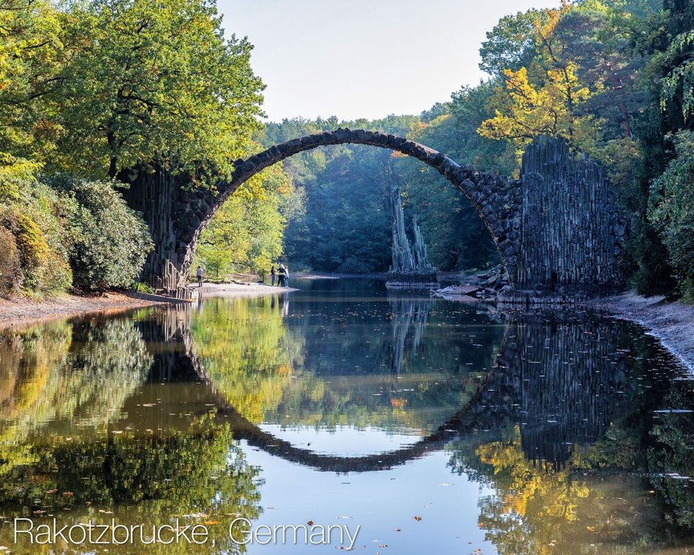 a bridge over water with trees and rocks