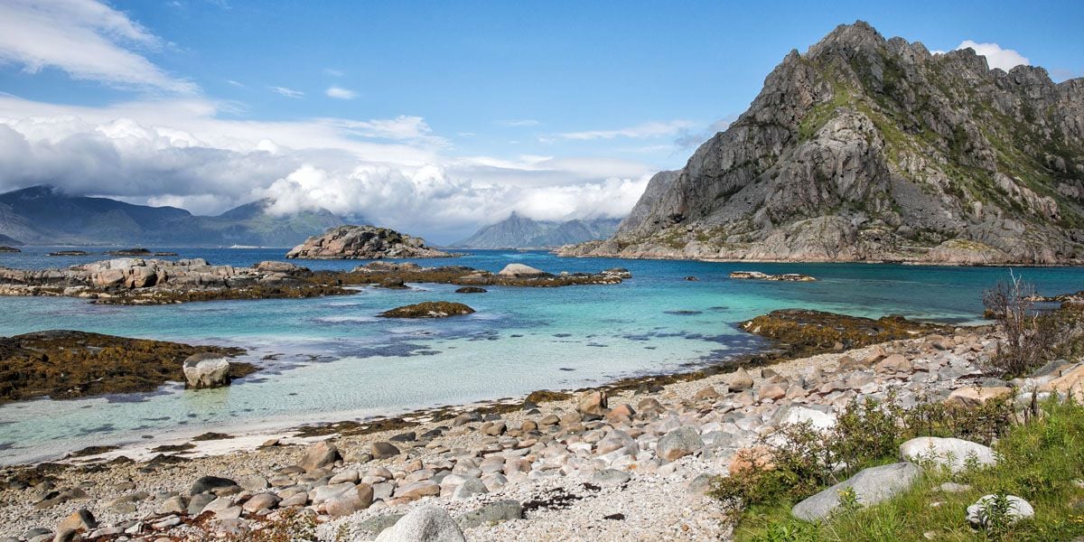 a rocky beach with mountains and blue water
